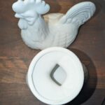 Vintage white porcelain rooster covered candy dish with lid removed, showing diamond-shaped handle cutout and interior of base bowl